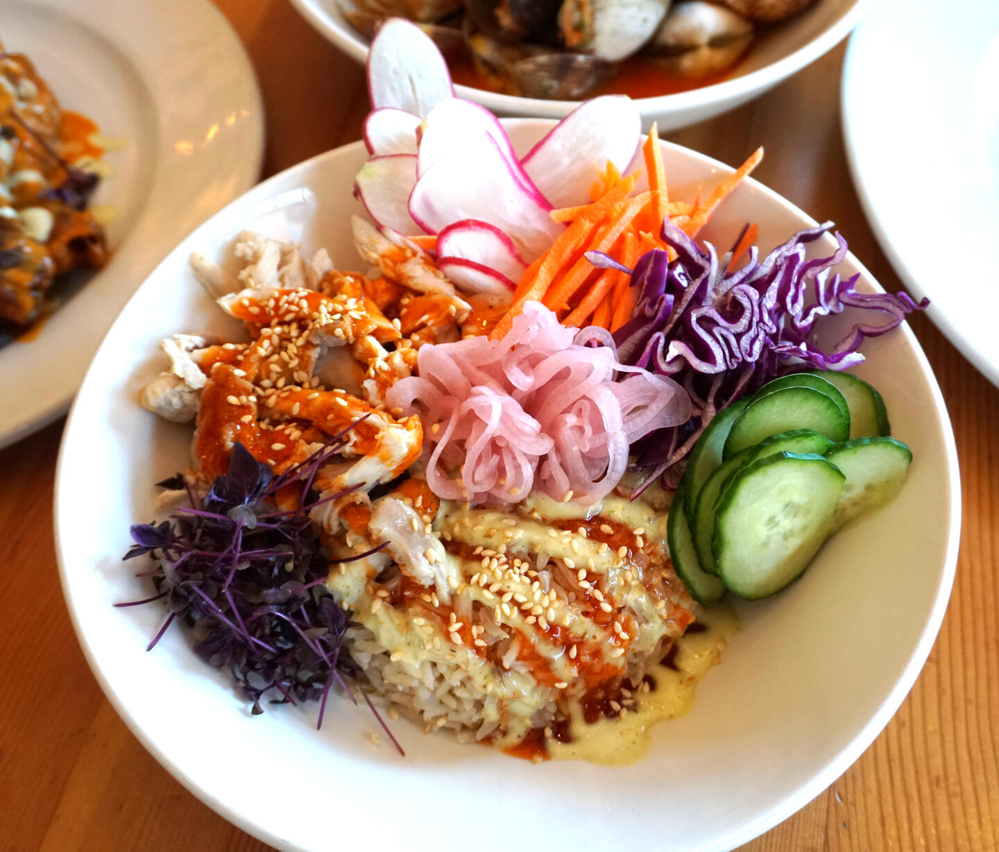 Pulled roasted chicken bowl with brown basmati rice, lemon herb vinaigrette, shredded red cabbage, julienne carrot, shaved cucumber and radish, pickled shallots, micro sprouts, honey hot sauce, serrano chili mayo and toasted sesame seeds, available at Swan