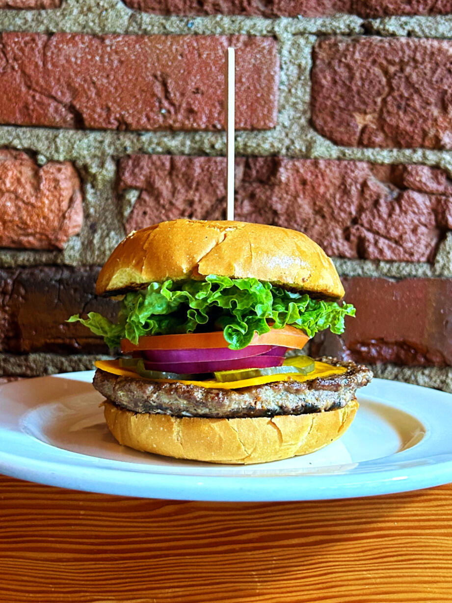 a half pound of organic, grass fed beef served on an Irene's bakery brioche bun with lettuce, tomato, onion, pickle & mayo served with your choice of house salad or fries, served at Swans Pub in Victoria, BC